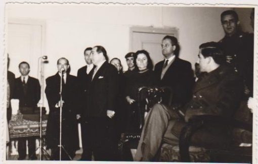[Αλεξανδρούπολη, Βασιλείς]: Ασπρόμαυρη φωτογραφία πιθανόν από την τελετή παραδόσεως βιβλιαρίων στις "άπορες κορασίδες", ο Διάδοχος Κωνσταντίνος παρακολουθεί τον ομιλητή [Διευθυντή του Υποκαταστήματος της Εθνικής Τραπέζης;], Φωτο Α. Δαΐδη, Αλεξανδρούπολις, 13 Δεκεμβρίου 1960, διαστάσεις 14Χ9
