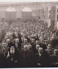 [Σέρρες]: Φωτογραφία, στο πίσω μέρος σημειώνεται με μολύβι: "Από το Συνέδριο Δήμων και Κοινοτήτων Ν. Σερρών. Εις την πρώτη σειρά ο Σεβασμιώτατος Σιδηροκάστρου...οι βουλευταί Σερρών κ. Μόντζαλας και Μηταφίδης / 14,15 και 16 Μαρτίου 1955", ασπρόμαυρη, διαστάσεις 18Χ12,  τσάκισμα στο επάνω μέρος